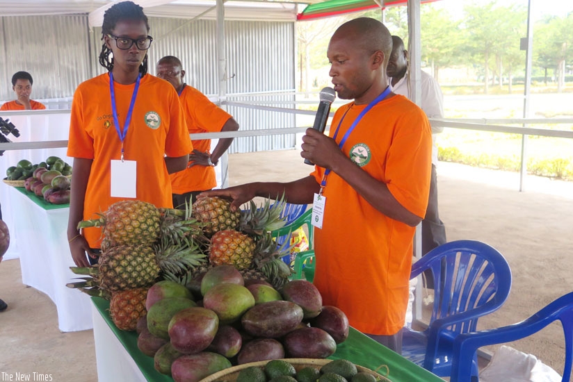An exhibitor explains the detail of his fruit produce to showgoers. (Theogene Nsengimana)rn