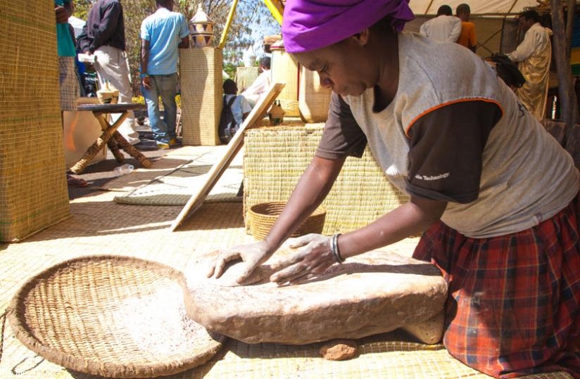 Mary Mukanyandwi from Musanze District demonstrates how millet is ground in the traditional Rwandan culture during last year's Umuganura expo at Amahoro Stadium in Kigali. (Timothy Kisambira)