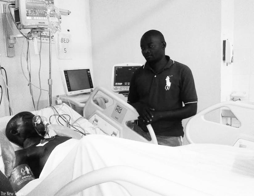 Ntahondereye on his bed at University Teaching Hospital of Kigali. Nshuntiyabose, his caretaker (right), says his brother-in-law's near recovery is almost miraculous.  (Elizabeth Buhungiro)