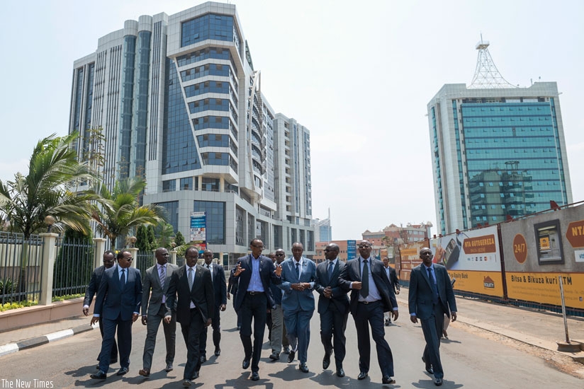 President Kagame (C) leads business operators and government officials to Kigali City Hall after inauguration of M. Peace Plaza building (background left) yesterday. rn(Village Urugwiro)