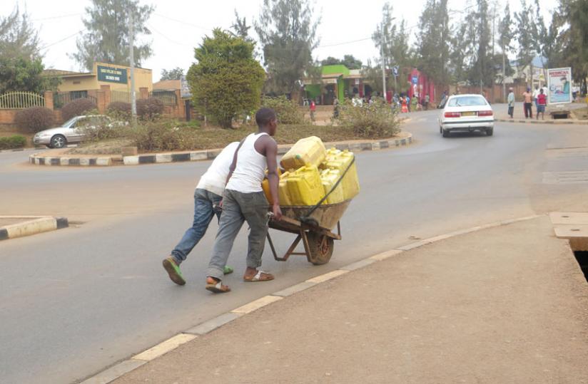 Two young men ferry jerrycans of water in Gikondo, a city suburb. (File)