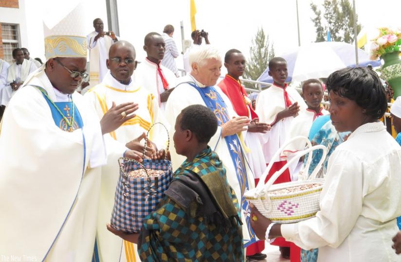 Monsignor Cu00e9lestin Hakizimana, the bishop of Gikongoro Diocese, gives blessings to Christians as they offer alms at Kibeho Holy Land in Nyaruguru District on Saturday. (Emmanuel Ntirenganya)