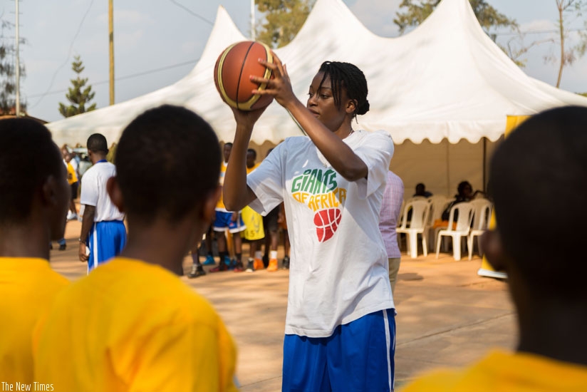 Nigerian-born British player Tei Fagbenle teaches kids the basics of shooting at Rafiki community centre in Nyamirambo. (Timothy Kisambira)