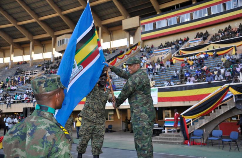 RDF Chief of Defence Staff, Gen Patrick Nyamvumba, receives the EAC flag from his Ugandan counterpart Gen Edward Katumba Wamala (L) at Namboole Stadium in Kampala, yesterday, signifying hand over of hosting rights to Rwanda for the next EAC Military Games edition due 2016. (Courtesy)