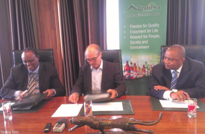 L-R: Bacyaha, Hall and Philip Ejiofor, Bralirwa's finance director, examine the loan deal documents. (Peterson tumwebaze)