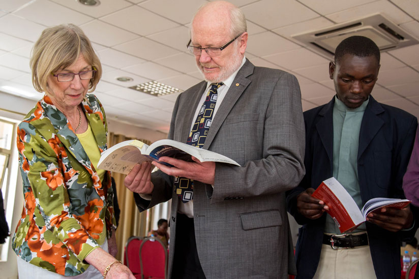 Prof James McWha, the vice-chancellor of the University of Rwanda (C), his wife who is an occupational therapist Lindsay McWha and a student read  books at the launch in Kigali yesterday. (All photos by Doreen Umutesi)