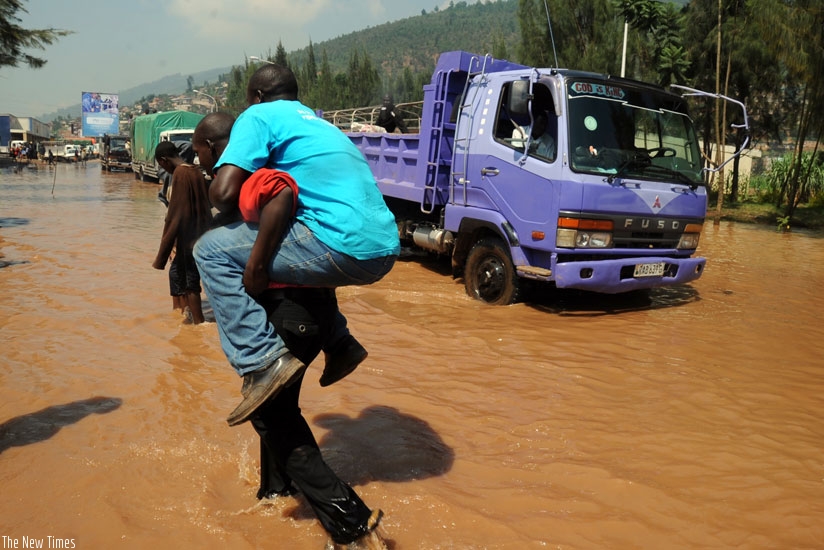 A man is carried across the flooded Nyabugogo road. EALA members want partner states to promote awareness campaigns in order to reduce vulnerability. (File)