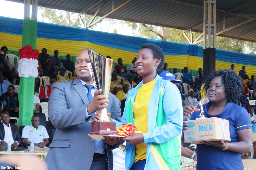 State Minister for  Education Olivier Rwamukwaya (L) hands over the volleyball trophy to Inderabarezi captain  Jacqueline Uwamariya. (E. Ntirenganya)