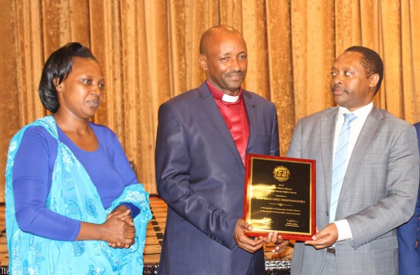 Rev Munyamasoko (C), flanked by his wife Mujawingabe, is congratulated by RGB CEO Prof Shyaka at the event to celebrate his award in Kigali on Tuesday. (Michel Nkurunziza)