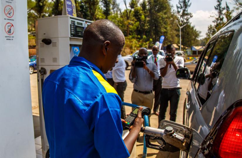 Remy Rugayabahunga, a fuel pump attendant with SP Rugunga service station in Kigali, refills a vehicle as he bills using electronic visa billing machine during the launch of the card-based electronic payment yesterday. (Timothy Kisambira)