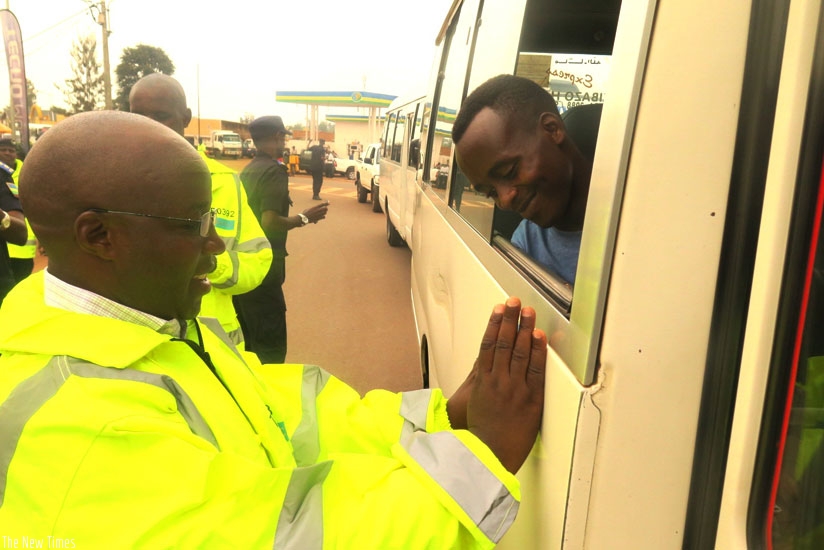 Nzahabwanimana attaches a safety precaution sticker on an omnibus in Kayonza yesterday. (Stephen Rwembeho)