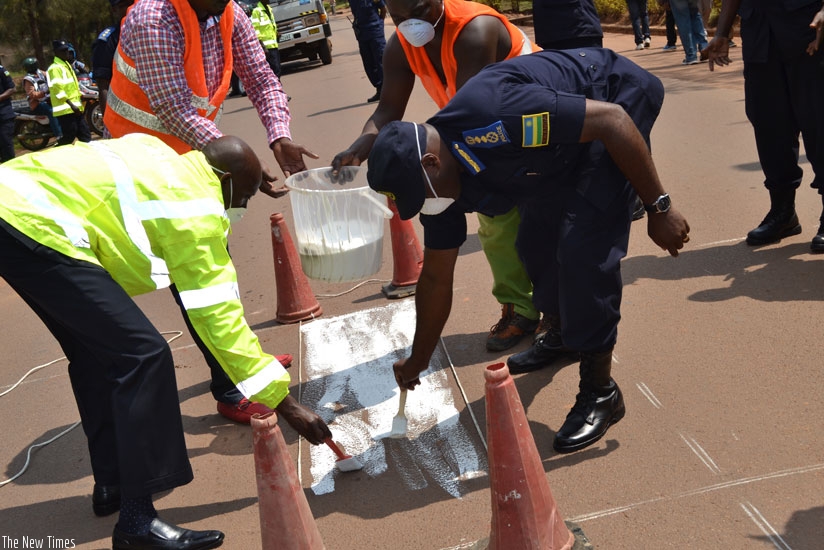 Local Government minister Francis Kaboneka and IGP Emmanuel Gasana paint a zebra-crossing in Kicukiro, Kigali, at the launch of the 'Police Month' yesterday. (Courtesy)
