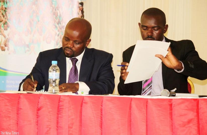 Nsengimana (left) and Shyerezo sign youth Imihigo yesterday. (Frederic Byumvuhore)