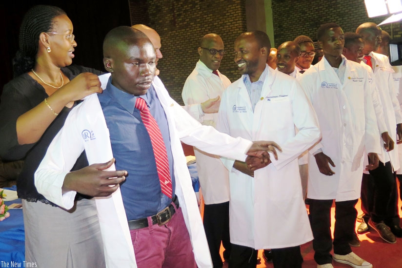 Dr Hakiba (L) dresses Theogene Nteziyaremye, a medical student, in a white coat during the White Coat Ceremony in at the UR's campus in Huye District on Friday. (Emmanuel Ntirenganya)