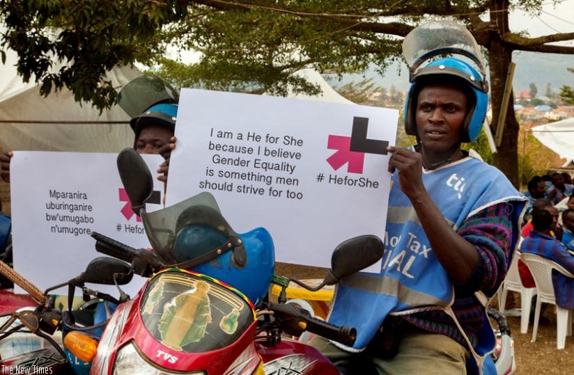 Tax-moto operators Egide Musangwa (R) and  Jean Baptiste Uhawenimana pose for a photo with banners declaring their commitment to HeforShe campaign. (Faustin Niyigena)