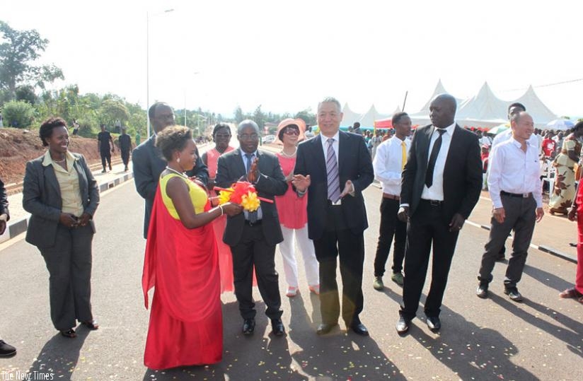 A lady usher picks the ribbons after the cutting ceremony during the inauguration of the Kabuga-Masaka road on Tuesday. The ribbon was cut by Fidele Ndayisaba, the mayor of the City of Kigali (behind the usher), Nzahabwanimana (C), Shen (2nd R) and Jules Ndamage, the mayor of Kicukiro. (Frederic Byumvuhore)