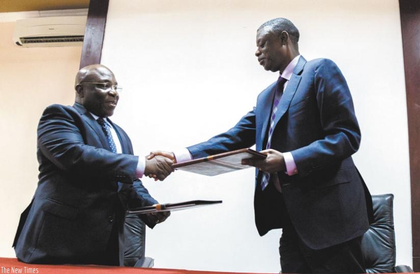 Ngoi-Mukena (L) and Kabarebe exchange documents in Kigali. (Timothy Kisambira)