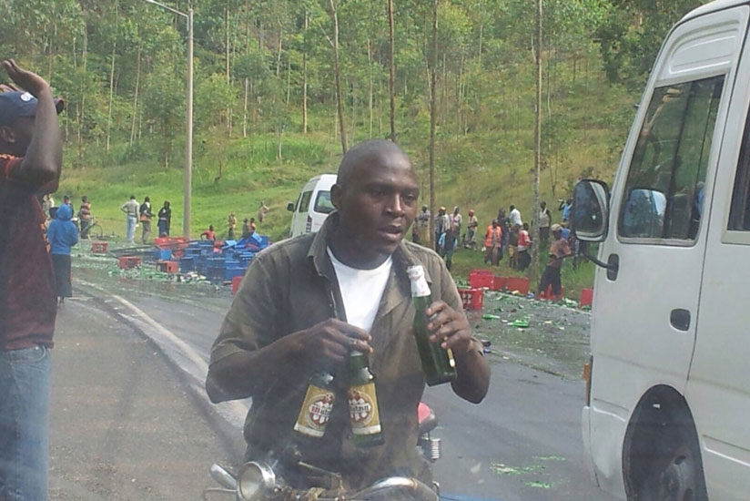 Some Gakenke residents enjoy free beer at the accident scene yesterday.  (J. Mbonyinshuti)