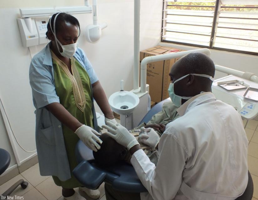 Dr Kiyaga (R) examines a patient with cavities. (Lydia Atieno)