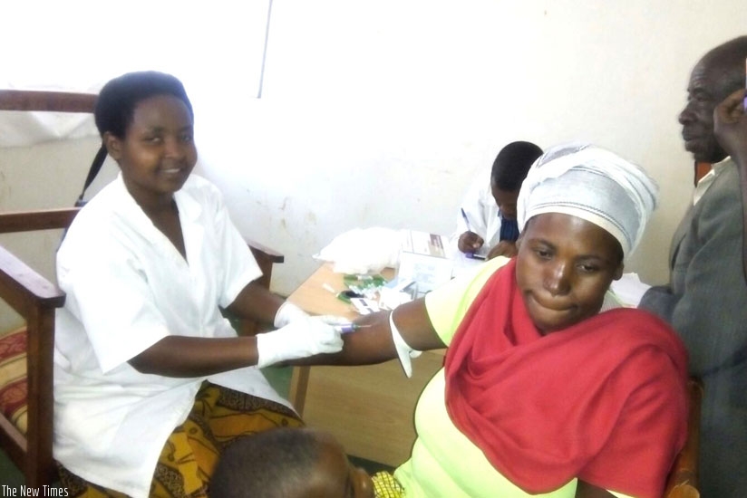 A nurse takes blood sample for HIV testing from a woman. (S. Rwembeho)