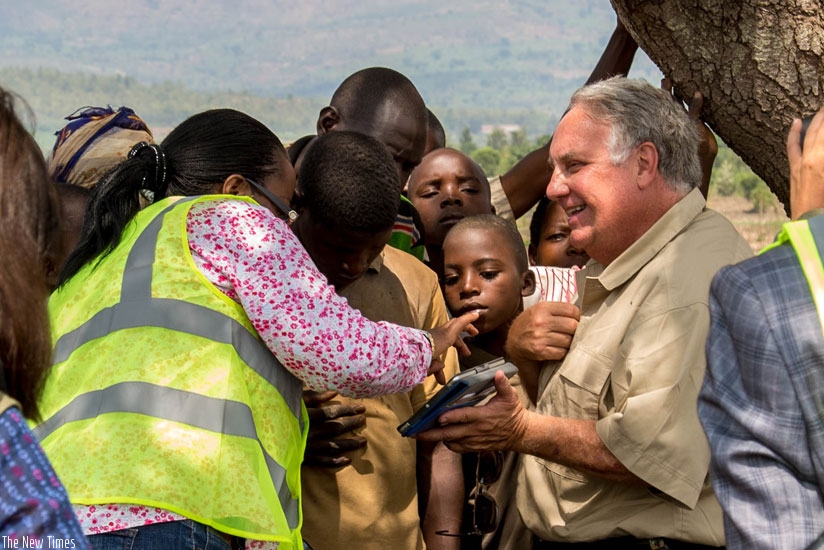 Howard G. Buffett (R) excitedly shows farmers how the irrigation project will look like as Dr Gerardine Mukeshimana, the minister for agriculture (with back to camera), translates for the farmers. rn(All photos by Doreen Umutesi)