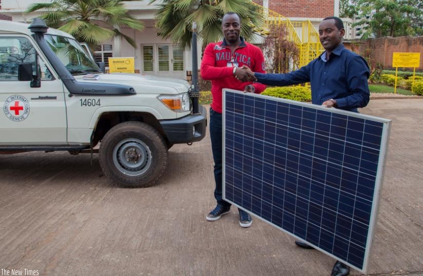 Rugero (R) hands over the solar panel to ICRC's Dukuze on Tuesday. (Faustin Niyigena)