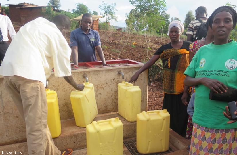 People fetch water from a public tap in Bitoma I village. The water supply  system was built with the support of Japan International Cooperation Agency. (Theogene Nsengimana)