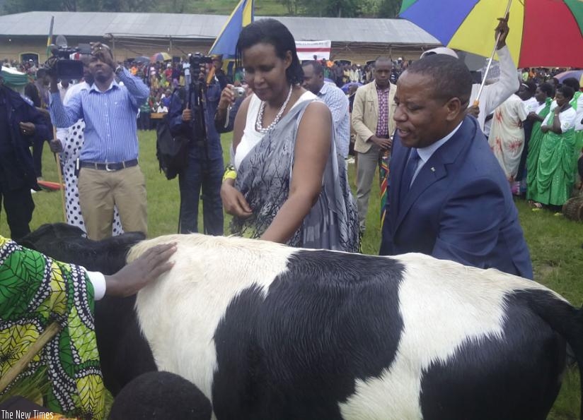 Gasinzigwa (L) and Bosenibamwe, hand over a cow to some rural women at the event in Gicumbi. (Theogene Nsengimana)