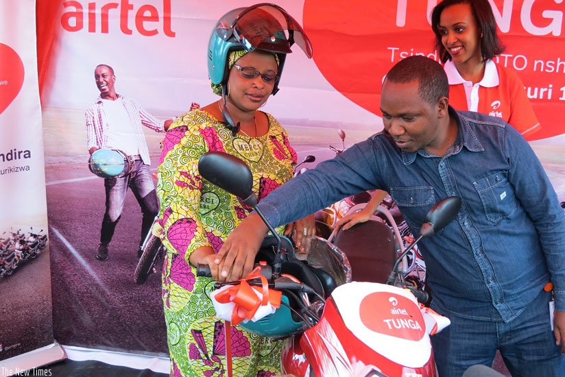 Urayeneza (left) is guided by Airtel staff to start the motorcycle. (Courtesy photo)