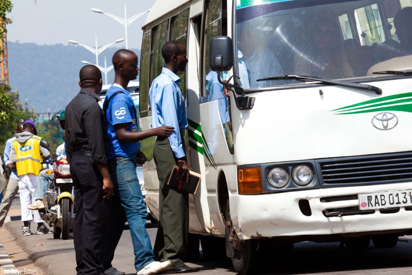 Commuters board a city bus. (Timothy Kisambira)