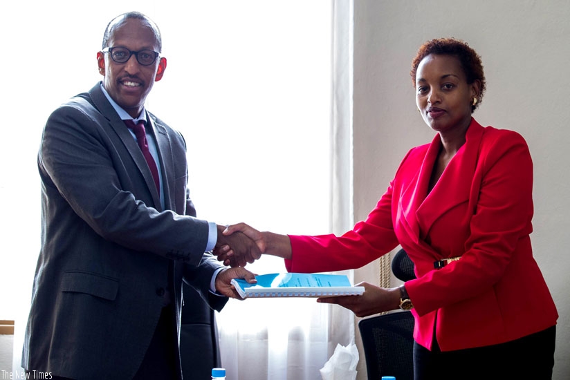 Maurice Nyaruhirira, the general manager of Horizon Construction (L), exchanges documents with  Murora yesterday. (Timothy Kisambira)