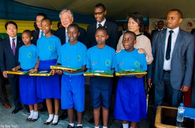 Primary school pupils pose for a photo with guests after receiving educational materials from a South Korean firm at Kimihurura Primary School on Friday. (Teddy Kamanzi)