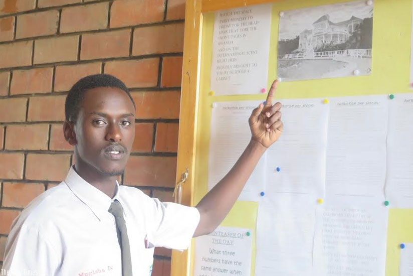 Mugisha shows off one of his drawings which is displayed on the notice board. / (All photos by Elizabeth Buhungiro)
