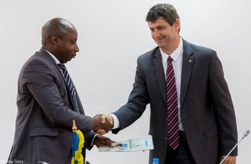 Mugiraneza (L) exchanges documents with Weiss in Kigali, yesterday, after the two signed agreements that will see Israel Electric Corporation help REG in its efforts to generate 563 megawatts capacity by 2018 and connect 70 per cent of the country's households to electricity. (Timothy Kisambira)