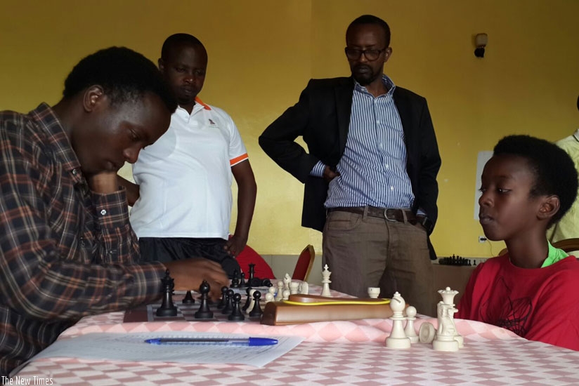 Ian Murara, right, gives University of Kigali (UK) student Elysee Tuyizere, 22, a hard time as his father, coach and teammate, Maxance Murara (in black coat), watches. ( J. Karuhanga)rn
