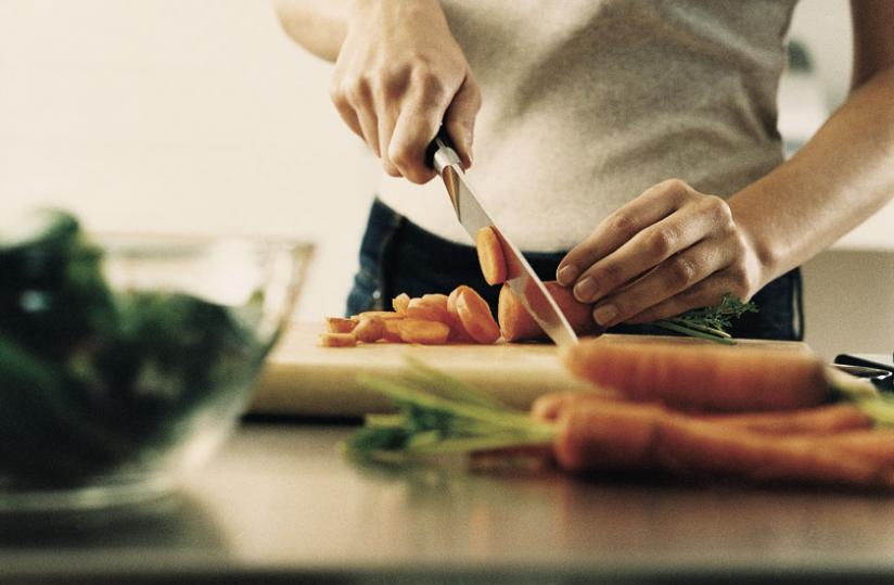A man chops carrots into small pieces. You must be careful about how you prepare vegetables and food/ 