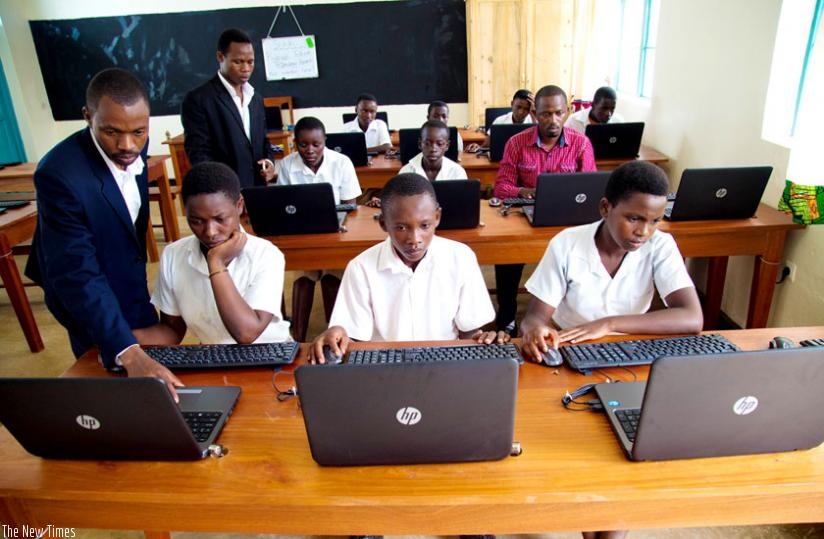 An IT instructor helps students of GS Masoro in Rulindo District with computer lessons in a laboratory. (File)