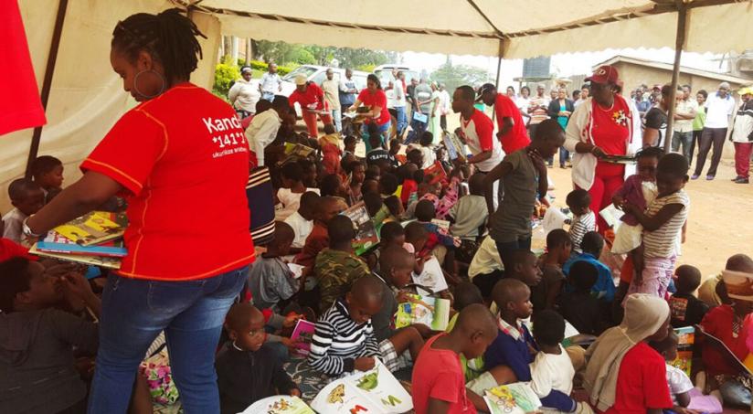 Airtel staff members distribute books to children at Ruganwa village Kacyiru. (Courtesy)