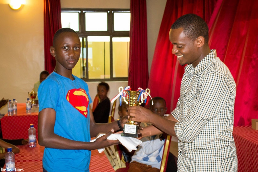 Kevin Marius Ikuzwe, 12, being handed the winner's trophy and a T-shirt by FERWADE Executive Secretary Alain Patience Niyibizi. (Courtesy)