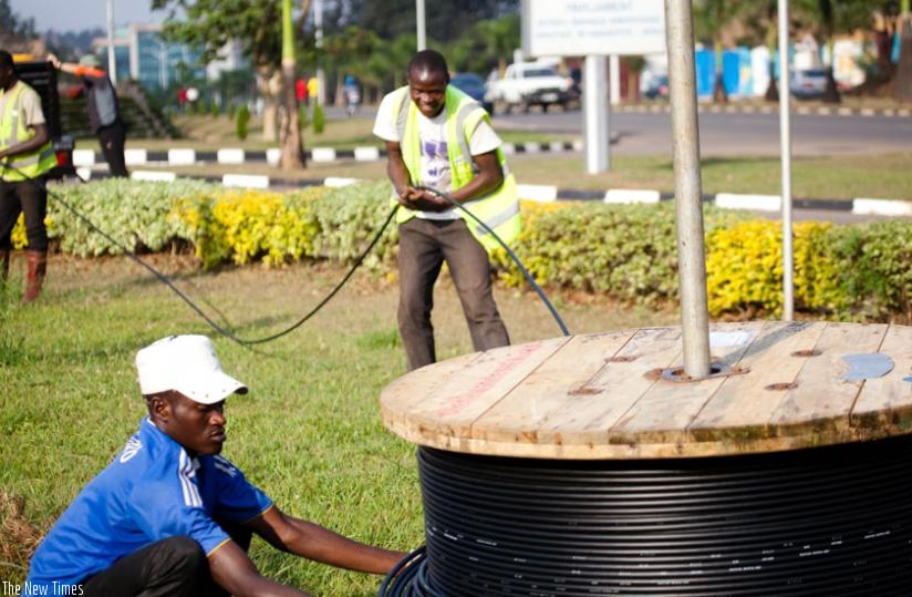 Workers lay optic fibre cables in Kigali. Infrastructure disparities could push the implementation of uniform roaming data rates beyond 2017. (File)