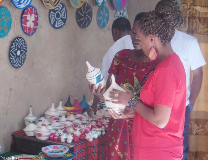 Kaitesi (right) admires some of the items made  by the group. Kaitesi's BoR is one of the main buyers of the products that include baskets  and wall marts. (Stephen Nuwagira)