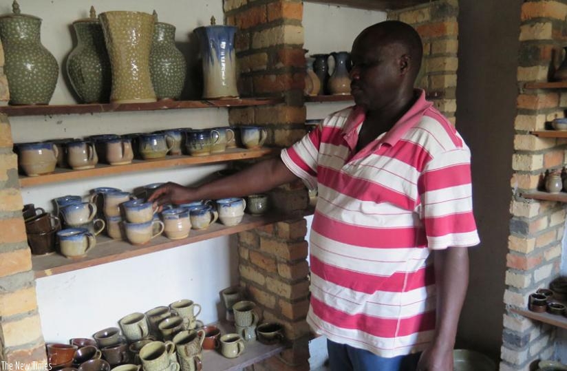 The president of Poterie Locale de Gatagara,Nshunguyinka, arranges some of the ceramic objects in  the shelves at the cooperative's workplace in Mukingo Sector on Tuesday.  (Emmanuel Ntirenganya)