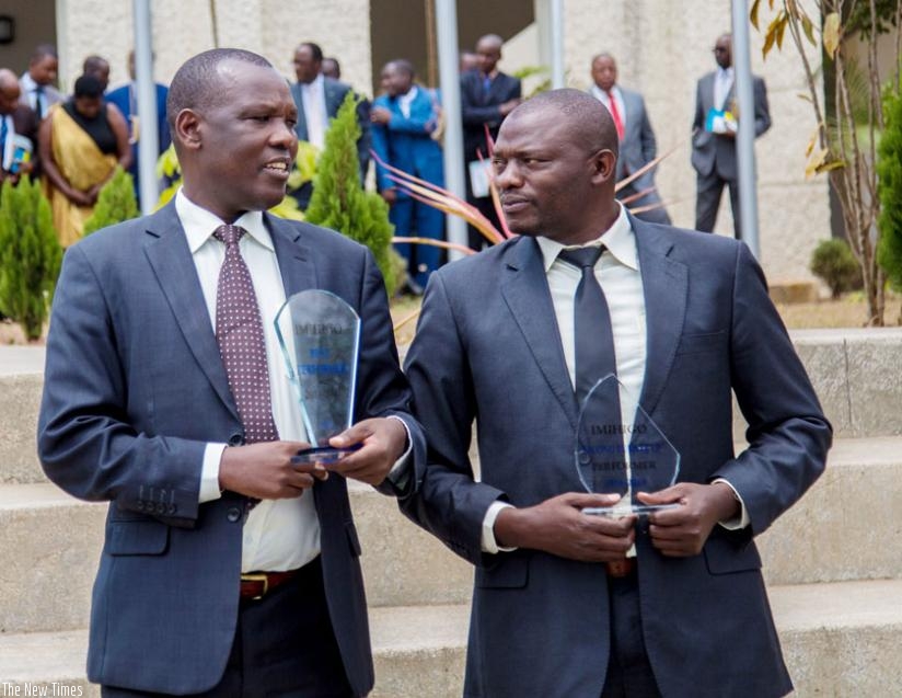 Huye mayor Eugene Kayiranga Muzuka (L) and his Ngororero District counterpart Gideon Ruboneza, chat after being awarded for their performance in Imihigo for 2013/14 financial year. (File)