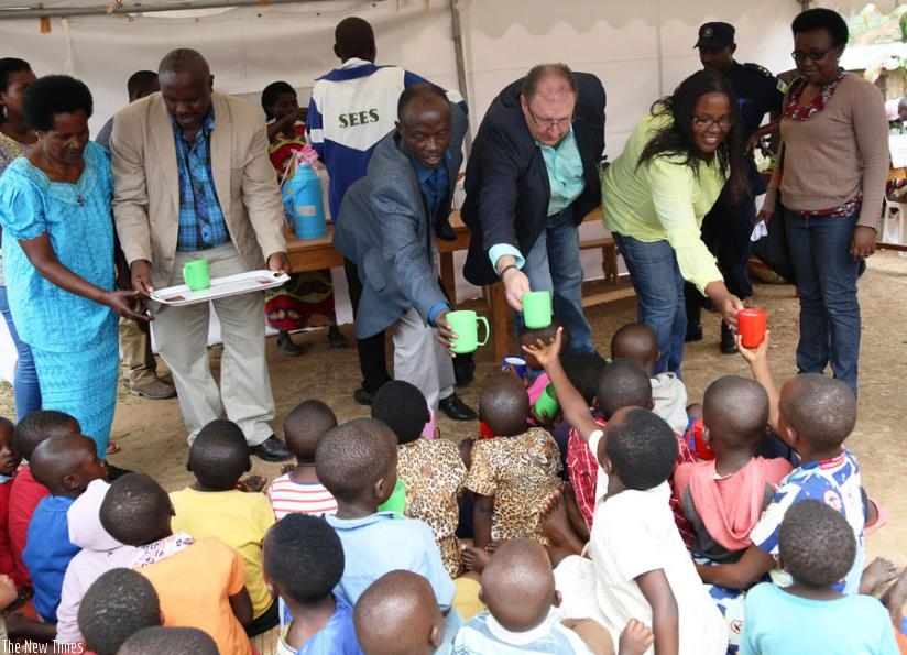 Schafer (center) and other officials serve milk to children in Rulindo District. (Jean d'Amour  Mbonyinshuti)