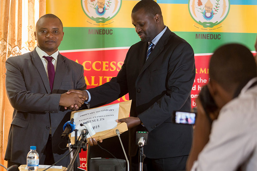 Olivier Rwamukwaya, the minister of state for primary and secondary education (L), receives a  parcel containing examination results from Janvier Gasana, the director general of Rwanda Education Board. (Timothy Kisambira) 