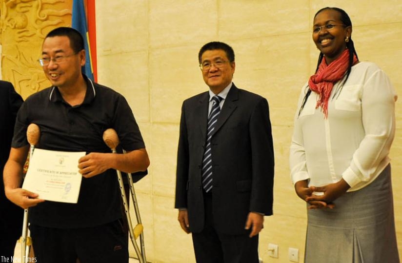 An outgoing nurse (L) shows off his certificate as Amb. Pan Hejun (C) and PS Hakiba look on. (Teddy Kamanzi)