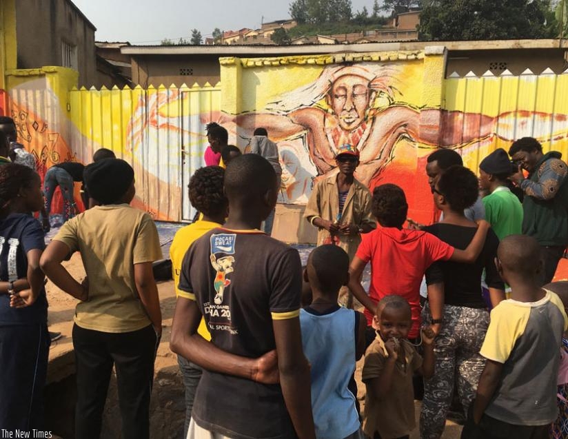 Youngsters listen to one of the artistes during the street painting  in Kimisagara on Saturday. (Eddie Nsabimana)