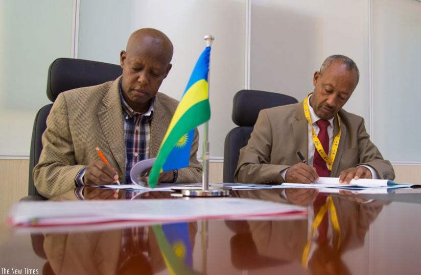 Silas Udahemuka the RCAA director general (left) and Gobena Guangul, the deputy director general of Ethiopia's Civil Aviation Authority, sign agreement documents last week. (Timothy Kisambira)