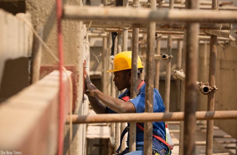 A worker at Kigali Heights construction site places a tile on the wall. (Timothy Kisambira)