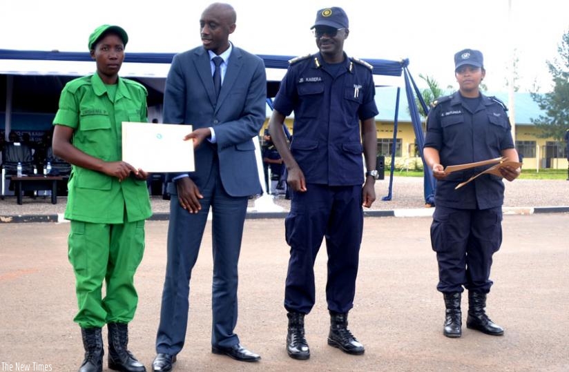 Minister Francis Kaboneka awarding a certificate to one of the DASSO best performer as the commandant of PTS, CP John Bosco Kabera looks on (Courtesy)